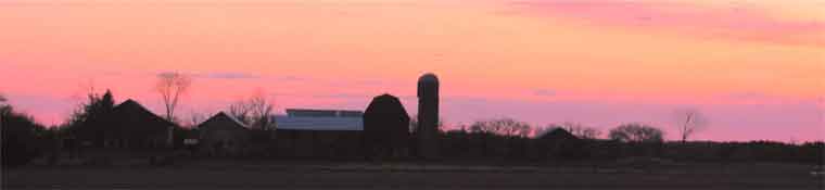 The silhouette of the Baker farm against the rosy hue of a Spring sunset.